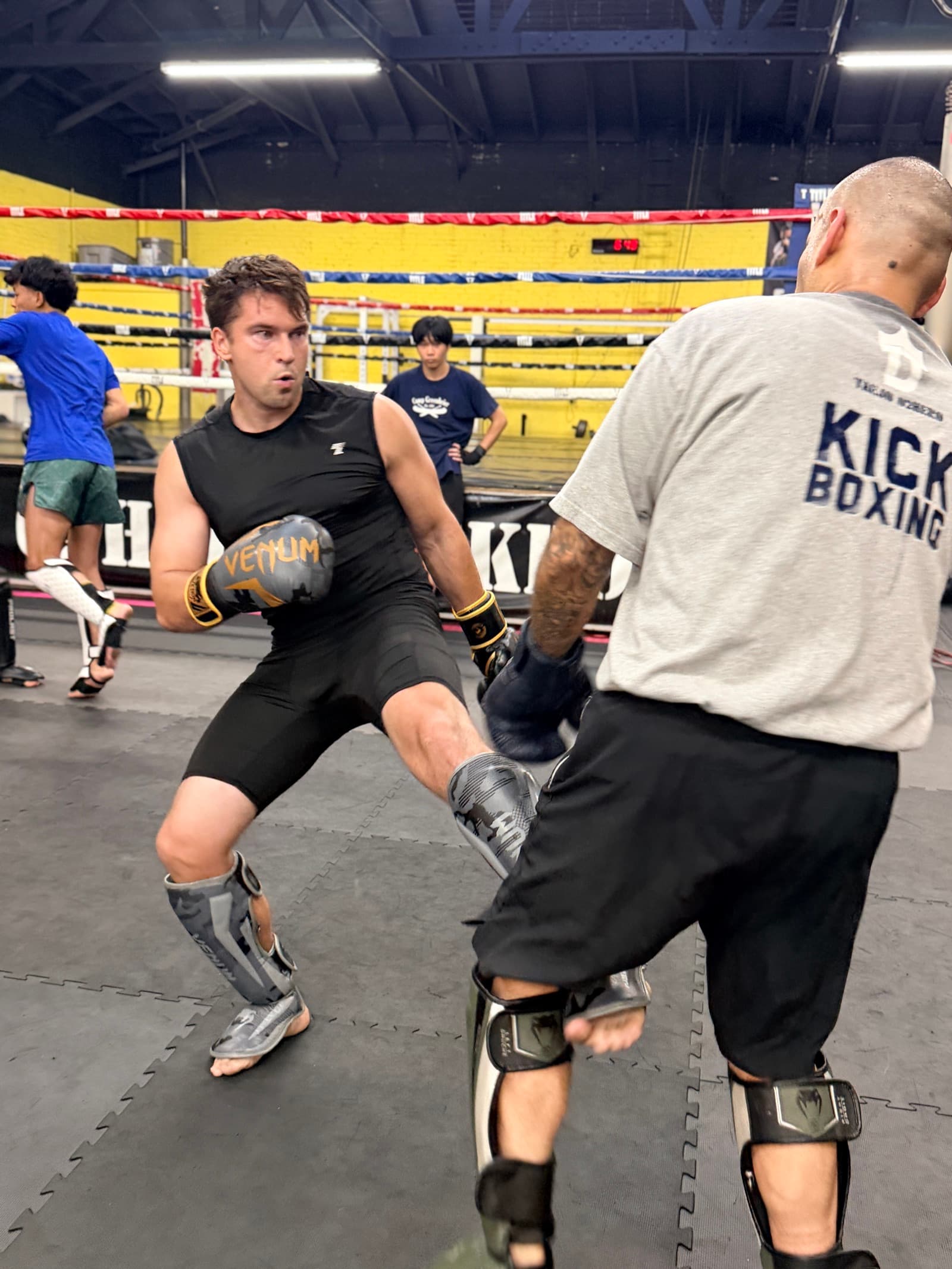 Member throwing a knee strike on Thai pads during a kickboxing class at TAEJO Kickboxing in Los Angeles